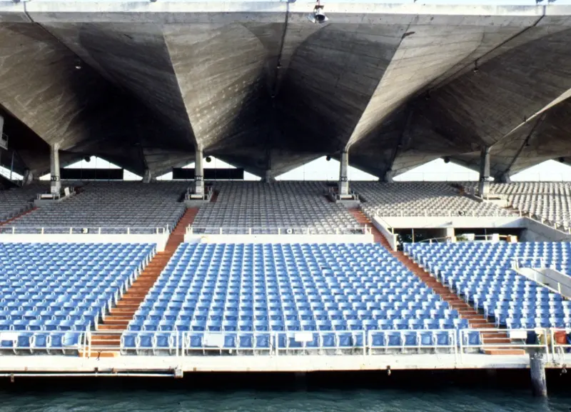 Cantilevered concrete roof over blue stadium seats